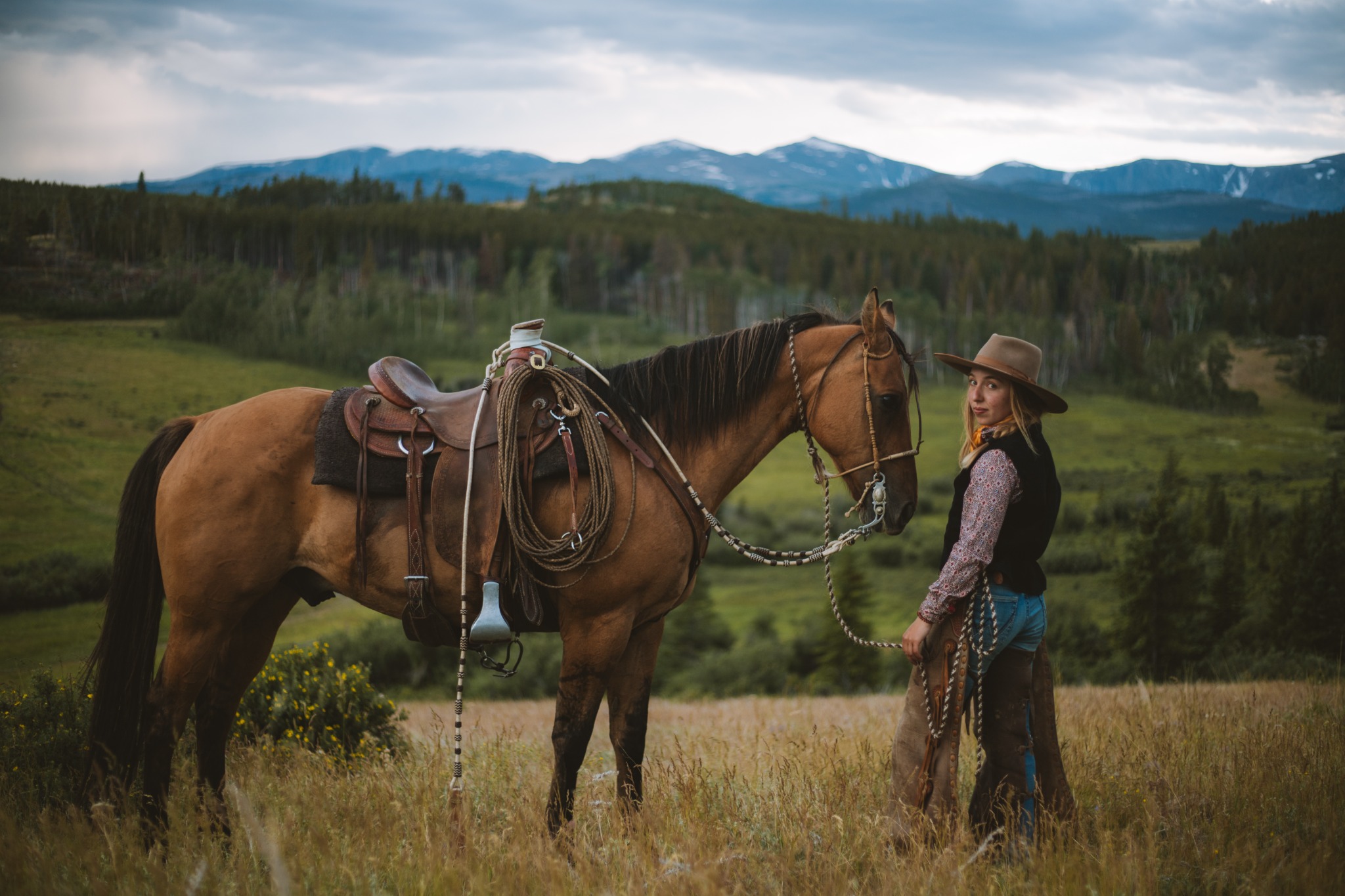 Horsewoman with saddled horse in the mountains